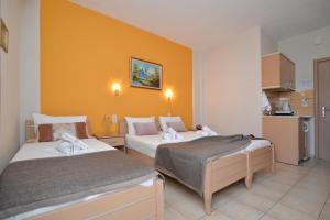 Habitación de hotel con 2 camas y pared de color naranja en Εlvina apartments, en Leptokarya