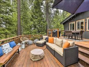 a patio with a couch and an umbrella on a deck at Tahoe Oasis - West Shore Chalet with View & Hot Tub! home in Homewood