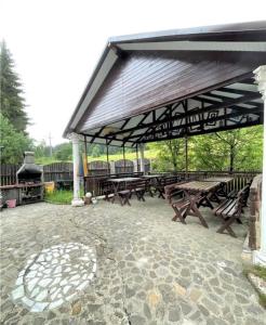 un pabellón con mesas de picnic de madera y parrilla en Casa Ticino Predeal en Predeal