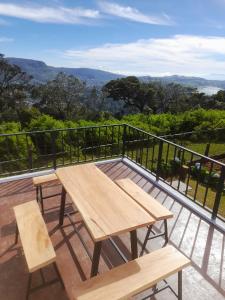 a wooden table and benches on a balcony with a view at Beraliya Cottage in Nuwara Eliya