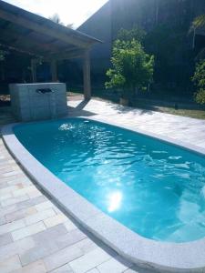een groot blauw zwembad in een tuin bij Chácara com piscina em Itanhaém in Itanhaém
