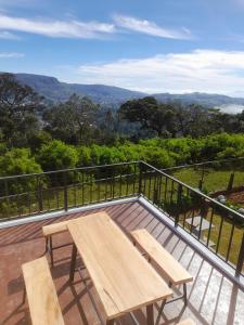 a wooden picnic table on a deck with a view at Beraliya Cottage in Nuwara Eliya