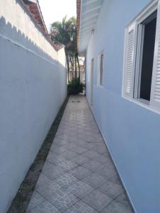 an alleyway between two white buildings with a palm tree at Ohayō sol in Bertioga