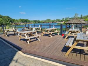 a wooden deck with picnic tables and a gazebo at Sherwood 33 in Carnforth