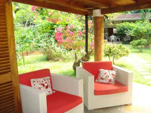 塔卡馬卡的住宿－Coté Sud - Unique Villa & Bungalows Intendance Road，门廊上设有两把椅子,享有花园的景色