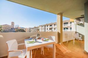 einen Tisch und Stühle auf einem Balkon mit Blick auf ein Gebäude in der Unterkunft Apartamentos Bressol in Port de Pollença