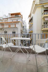 einen Tisch und Stühle auf einem Balkon mit Gebäuden in der Unterkunft New modern 2nd floor apartment in Thessaloniki