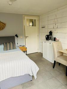 a bedroom with a bed and a table and a kitchen at By Onzz in Kamperland