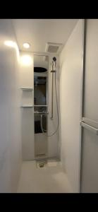 uma casa de banho com um chuveiro num quarto branco em すくもBOX em Sukumo