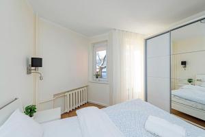 a white bedroom with a bed and a window at Riverfront 1BD Old Town Apartment by Hostlovers in Kaunas