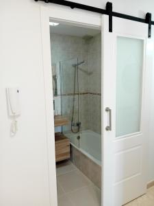 baño con ducha y puerta blanca en Pura Playa - Rías Baixas - Galicia, en Cangas de Morrazo