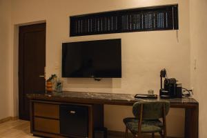 a desk with a television on a wall with a chair at Casa Continental Hotel Boutique & Suites - Adults Only in Mérida