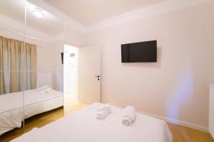 a bedroom with two beds and a tv on the wall at New modern 2nd floor apartment in Thessaloniki