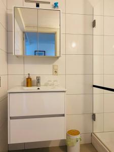 a white bathroom with a sink and a mirror at By Onzz in Kamperland