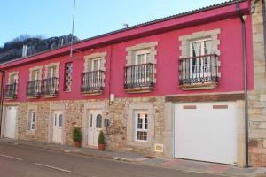 un bâtiment rouge avec des portes de garage blanches dans une rue dans l'établissement La Cuadra, à Cabornera