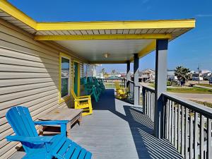 a porch with two blue chairs and a wooden table at Beachy Keen in Surfside