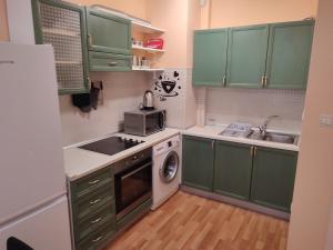 een kleine keuken met groene kasten en een wastafel bij Primorski Apartment in Varna