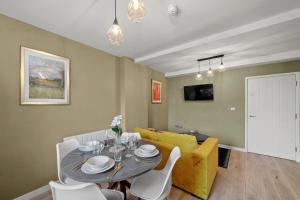a living room with a table and a yellow couch at BridgeCity Spectacular Morden 2 bedroom flat in Ashford Town Centre in Kent