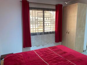 1 dormitorio con cama roja y ventana en Palm Villas Estate, en Bijilo