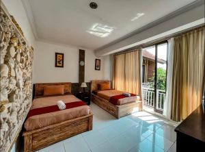 a bedroom with two beds and a balcony at Griya Umadui Bali in Ketewel