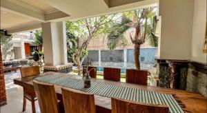 Griya Umadui Bali في Ketewel: غرفة طعام مع طاولة وكراسي والنخيل