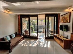 Griya Umadui Bali في Ketewel: غرفة معيشة مع أريكة وأبواب زجاجية منزلقة