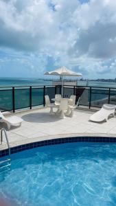 a swimming pool with chairs and an umbrella at Ocean Atlantic Praia de Iracema in Fortaleza