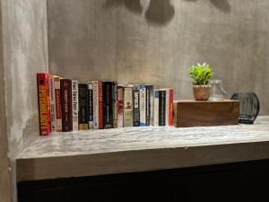 une rangée de livres sur une étagère avec une plante en pot dans l'établissement Dango Homestay, à Kuching