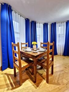 a dining room table with two chairs and blue curtains at The Three Musketeers, Porthos in Eastbourne