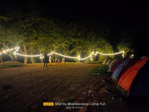 un uomo in piedi di notte accanto a un gruppo di tende di Bhandardara Campthrill Adventure a Bhandardara