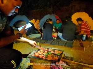 Un gruppo di persone seduti intorno a un tavolo che mangiano cibo di Bhandardara Campthrill Adventure a Bhandardara