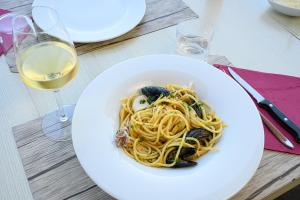 a white plate of pasta and wine glasses on a table at Residenza Principina in Principina Terra