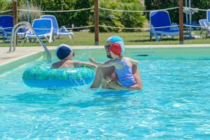 a man and a child in a swimming pool at Residenza Principina in Principina Terra