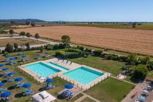 an overhead view of a pool with chairs and umbrellas and a field at Residenza Principina in Principina Terra