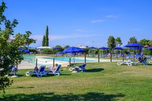 a group of people sitting in lawn chairs by a pool at Residenza Principina in Principina Terra