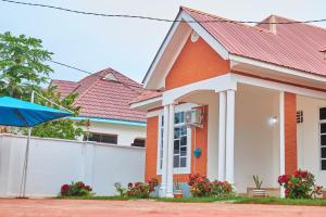 a house with a white fence and a red roof at Mama's Home Stay in Dodoma