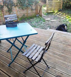 une table de pique-nique et une chaise sur une terrasse avec un chien dans l'établissement La petite cabane de Georges à Saint Brévin l'Océan, à Saint-Brévin-les-Pins