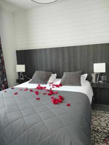 a bed with red rose petals on it at Hôtel La Réserve in Gérardmer
