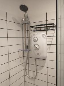 a shower with a shower head on a wall at Cosy Garden Studio Room in Hove