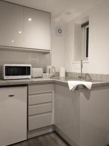 a kitchen with white cabinets and a microwave at Cosy Garden Studio Room in Hove