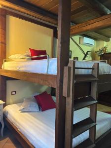 two bunk beds with white sheets and red pillows at Cascina Merlanetta in Alessandria