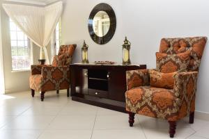 sala de estar con 2 sillas y espejo en Villa Palesa Guesthouse, en Grahamstown