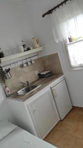 a white kitchen with a sink and a window at Zaira Studios in Skala Eresou