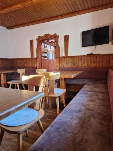 a restaurant with tables and chairs and a tv on the wall at Almhof Grub in Wagrain