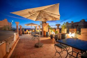 un patio con mesas y sombrillas por la noche en Riad Azia en Marrakech