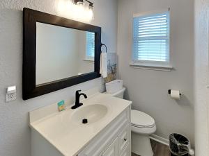 a bathroom with a sink and a toilet and a mirror at Beachy Keen in Surfside