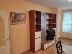 een woonkamer met een tv en een boekenplank bij Primorski Apartment in Varna