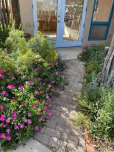 une passerelle avec des fleurs roses devant un bâtiment dans l'établissement Taos Mountain Views- Cozy Home-Special Rates, à El Prado