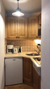 a small kitchen with wooden cabinets and a sink at Appartement Montagne Puy Saint Vincent 1800 - Résidence Dame Blanche 3 étoiles in Puy-Saint-Vincent