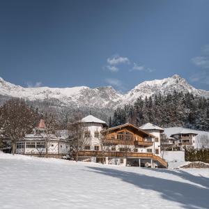 um resort na neve com montanhas ao fundo em Hotel Leitenhof 4 Sterne Superior em Scheffau am Wilden Kaiser